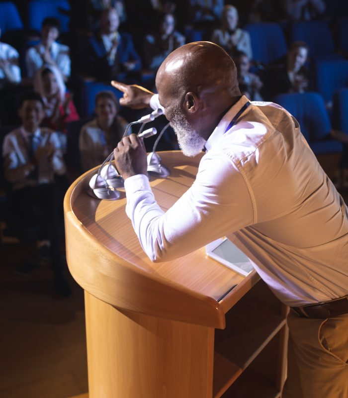 Businessman standing and holding speaker while asking question to the audience