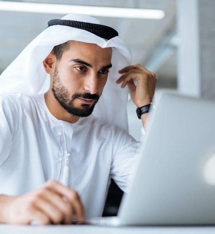 handsome man and woman with traditional clothes working in an office of Dubai