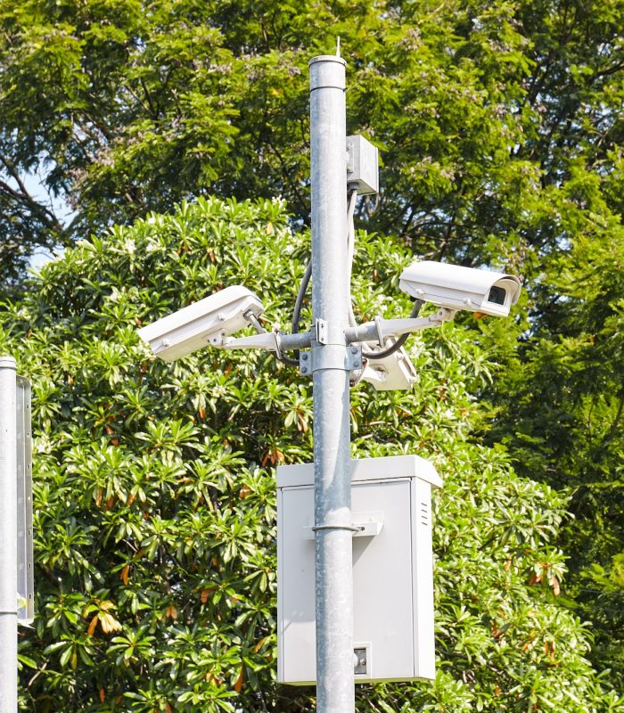 Security cameras or Surveillance CCTV outdoors in the public park with green tree background